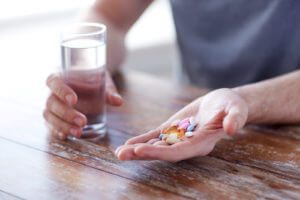 Person holding Acamprosate pills and a glass of water for alcohol recovery