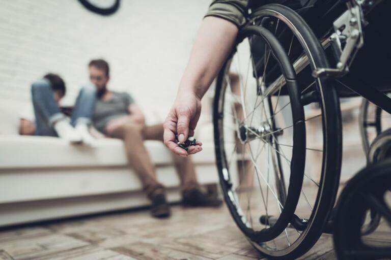 Person in wheelchair holding pills, symbolizing addiction and disability challenges