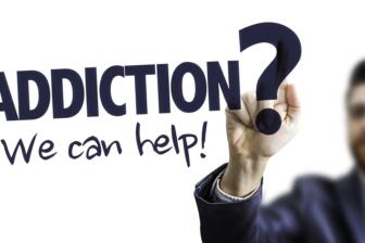 Hand writing "Addiction? We can help!" on clear screen, alcohol recovery