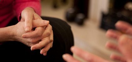 Hands clasped during an addiction recovery meeting, symbolizing support