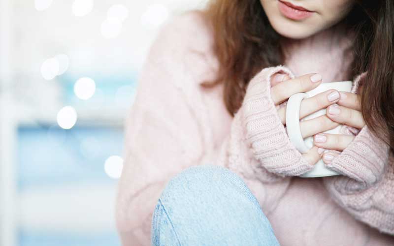 Woman holding a mug, symbolising comfort for addiction treatment at home.
