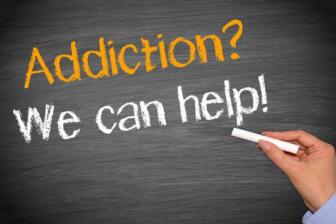 Hand writing "Addiction? We can help!" on chalkboard