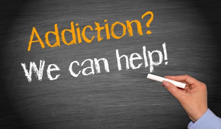 Hand writing "Addiction? We can help!" on chalkboard