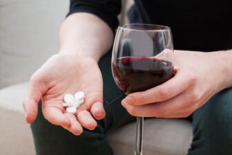 Person holding wine glass and pills, symbolizing alcohol and codeine risks