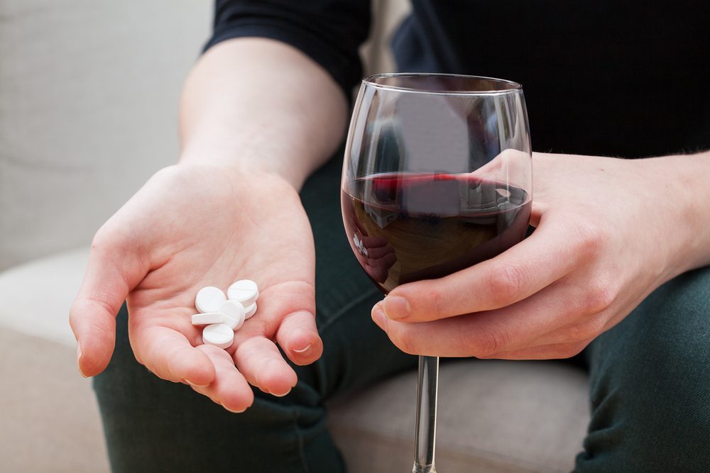 Person holding wine glass and pills, symbolizing alcohol and codeine risks