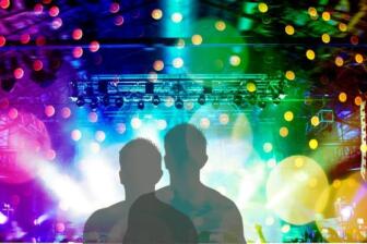 Silhouetted figures at a vibrant concert with colorful lights