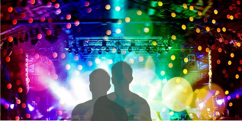 Silhouetted figures at a vibrant concert with colorful lights