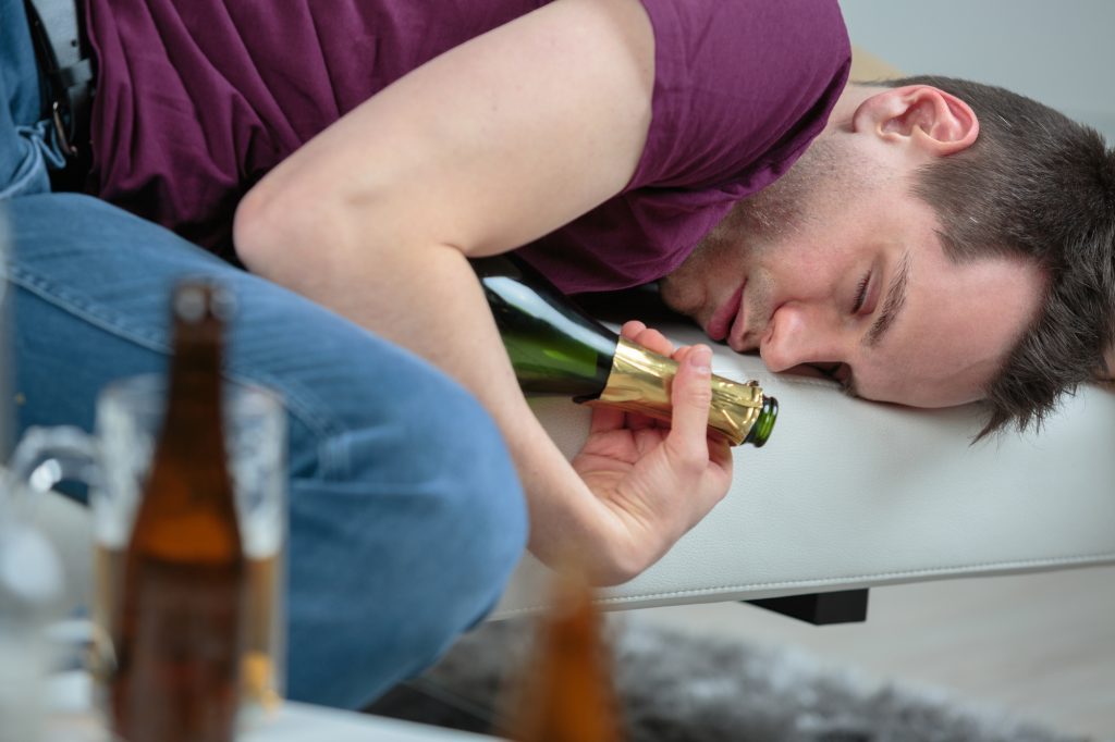 Man holding a bottle on couch, illustrating alcohol intervention