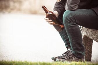 Person holding empty bottle, contemplating alcohol recovery journey