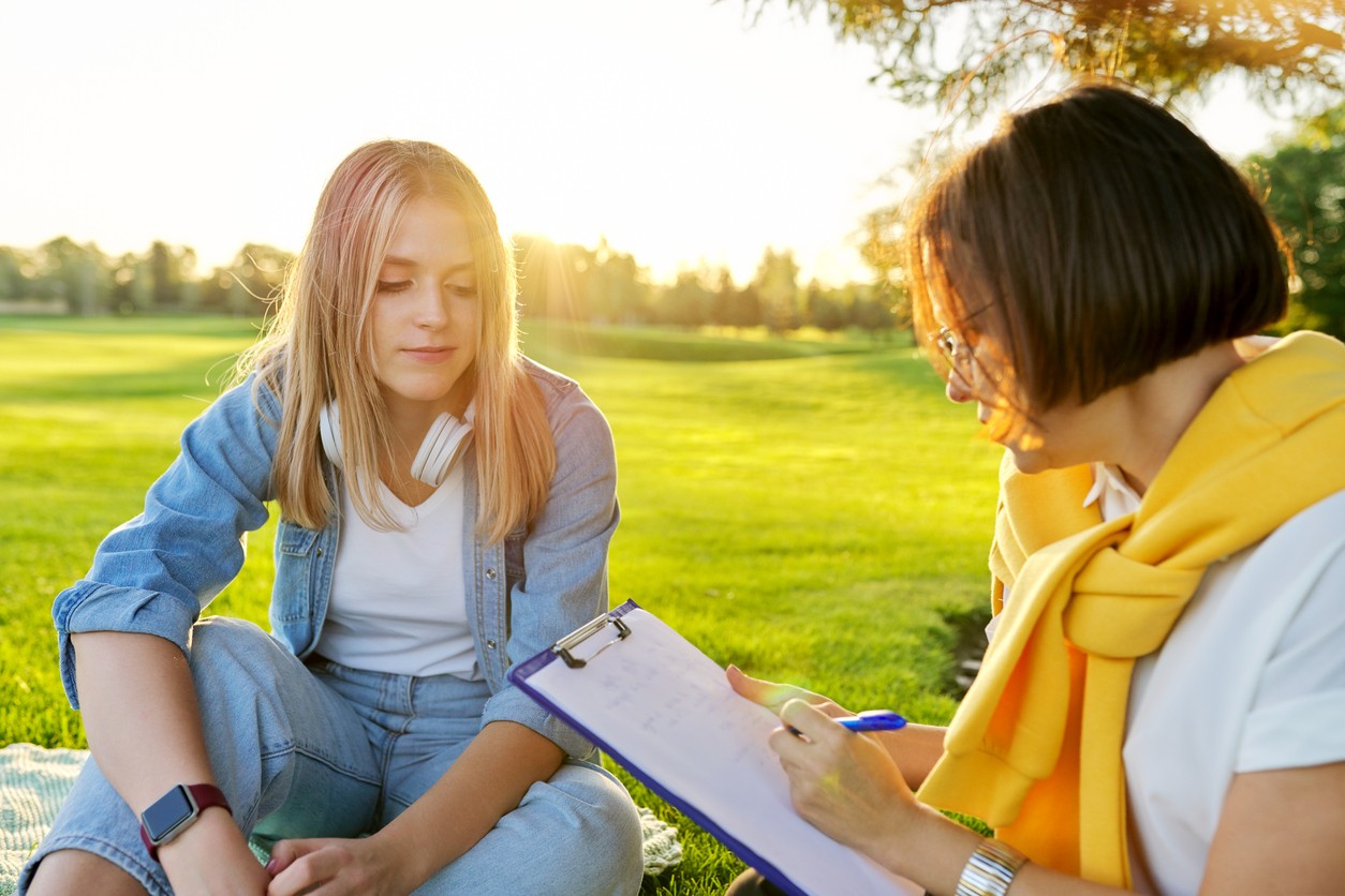 Young woman discussing recovery with a counselor outdoors