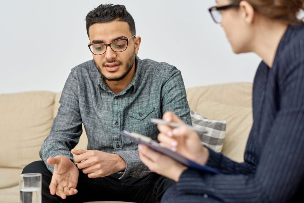 Man discussing recovery with therapist on a sofa