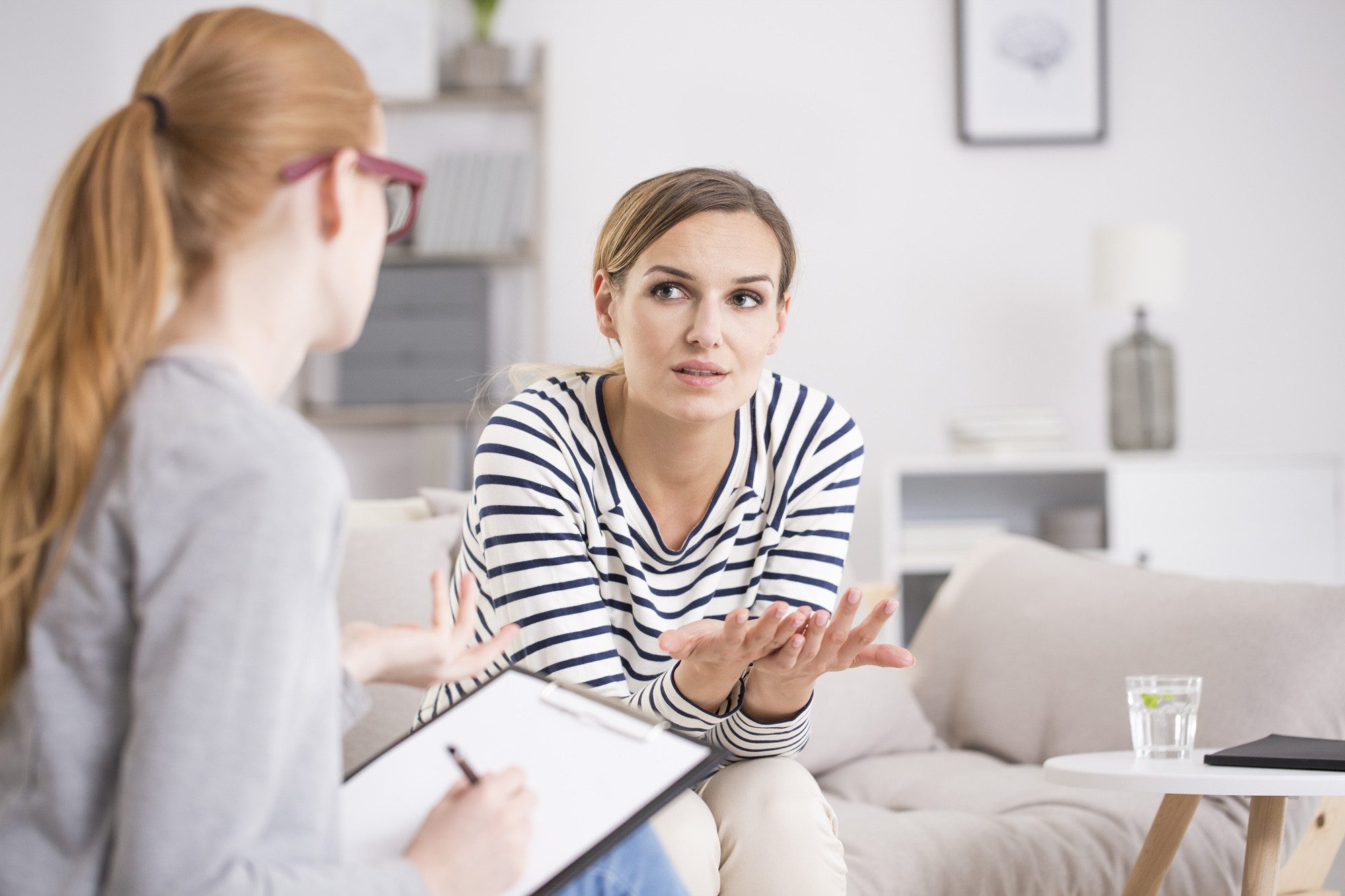Two women in a supportive therapy session discussing alcohol recovery.