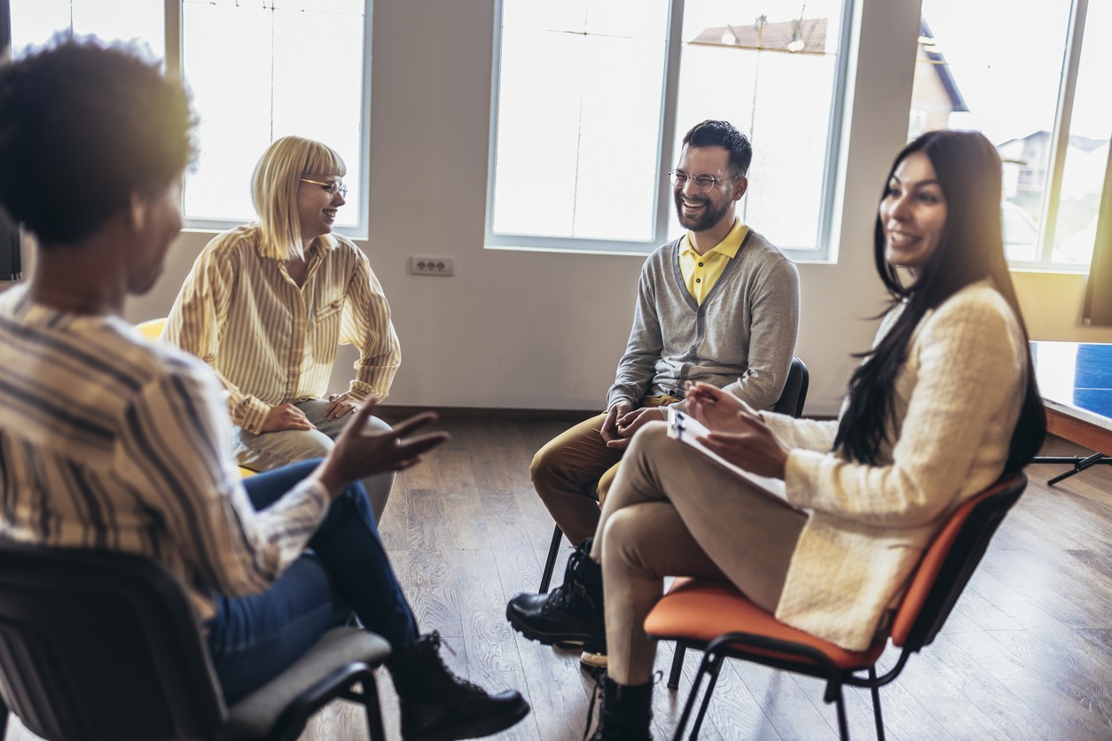 Group of people smiling in a circle during alcohol rehab Harborough session