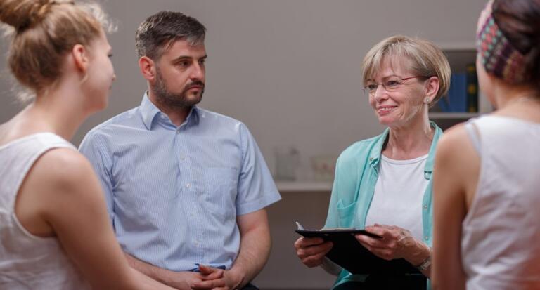 A support group discussing Alcohol Use Disorder recovery in rehab.