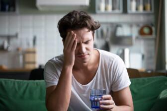 Man experiencing alcohol withdrawal symptoms holding a glass of water
