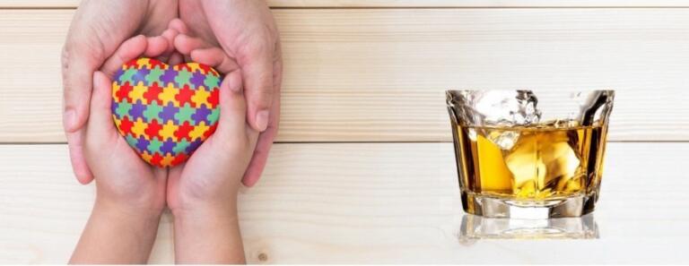 Hands holding autism puzzle heart beside alcohol glass, symbolizing autism and alcohol addiction