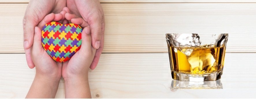 Hands holding autism puzzle heart beside alcohol glass, symbolizing autism and alcohol addiction