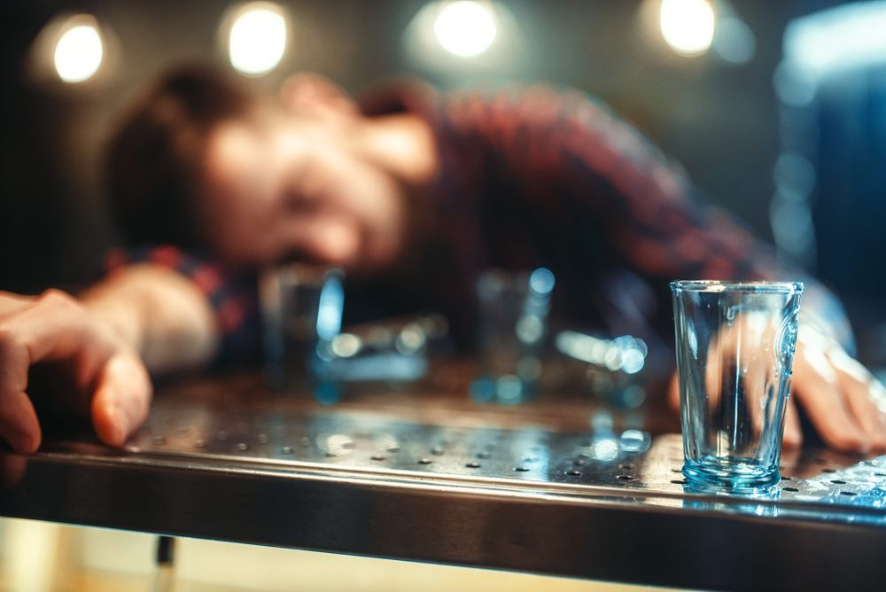 Person experiencing blackout drinking with empty glasses on table