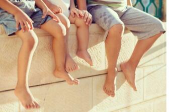 Three children sitting on a wall, legs dangling, symbolizing hope and recovery