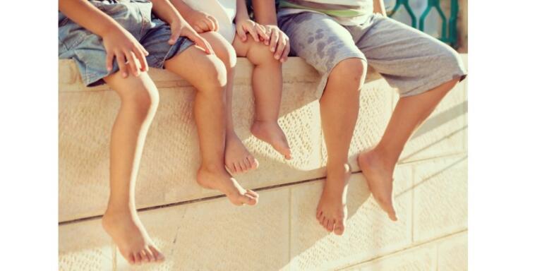 Three children sitting on a wall, legs dangling, symbolizing hope and recovery