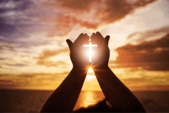 Hands holding cross at sunset, symbolizing faith in Christian rehab alcohol recovery.