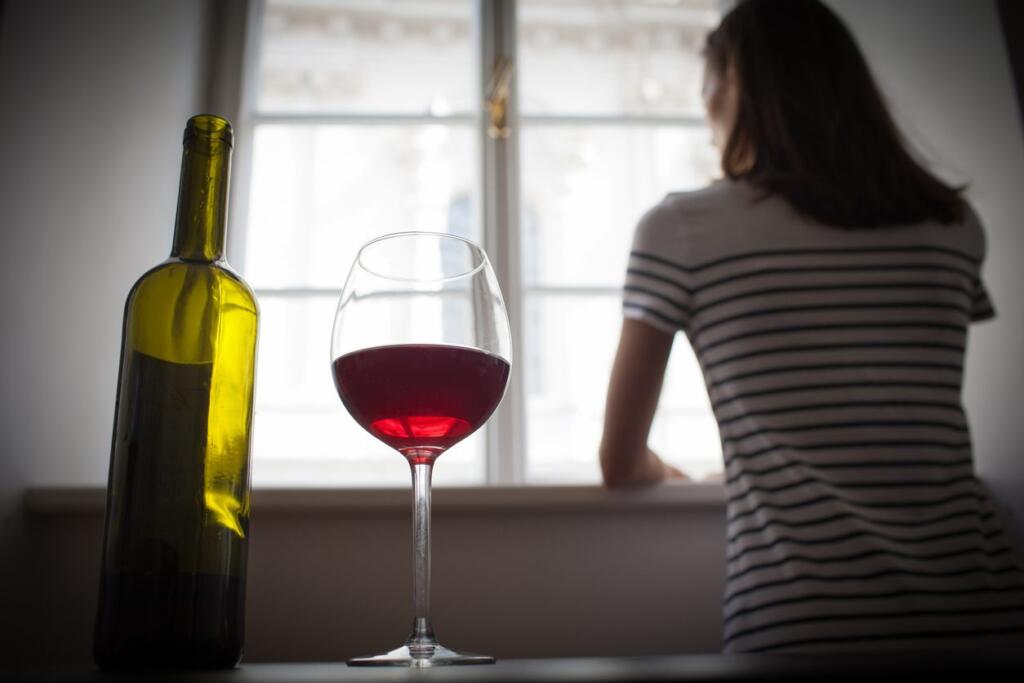 Person contemplating quit alcohol with wine bottle in focus