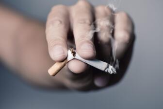 Close-up of hand crushing cigarette, symbolizing breaking addiction.