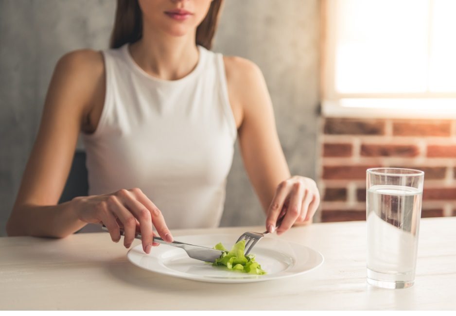 Person with plate of salad and water, highlighting eating disorders