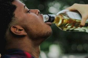 Person drinking from bottle, highlighting effects of alcohol consumption