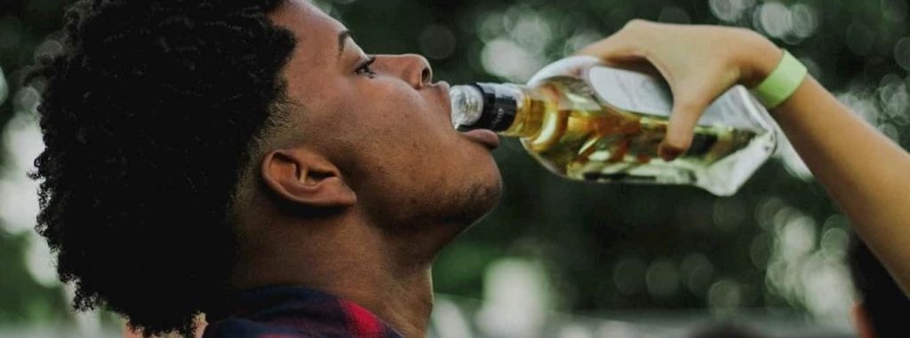 Person drinking from bottle, highlighting effects of alcohol consumption