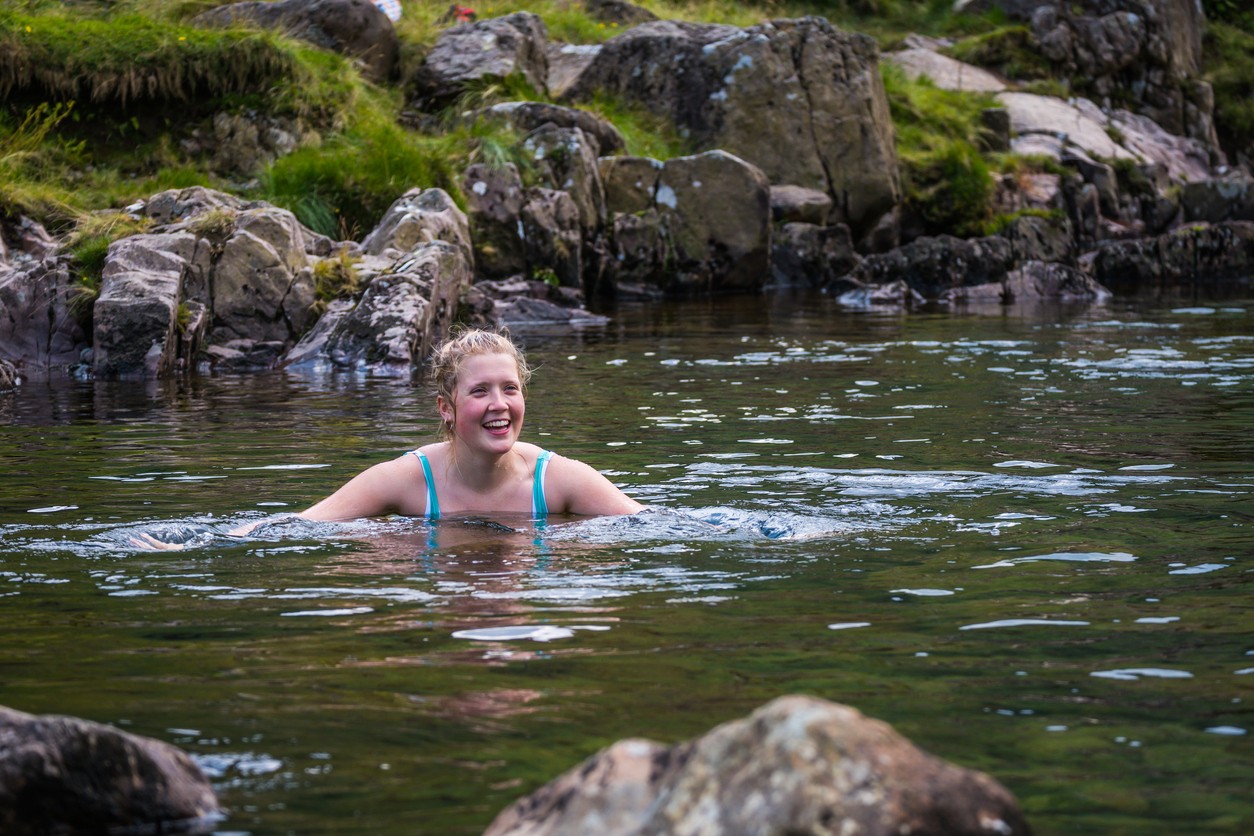 Woman swimming in nature, enhancing fitness and mental health during recovery