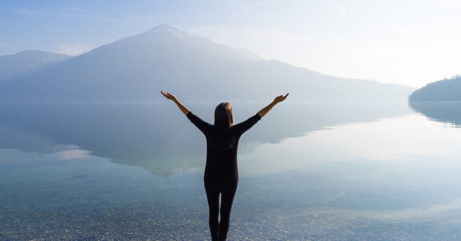Person embracing freedom by peaceful lake, alcohol recovery journey