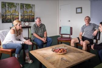 People in a supportive group therapy setting discussing recovery.
