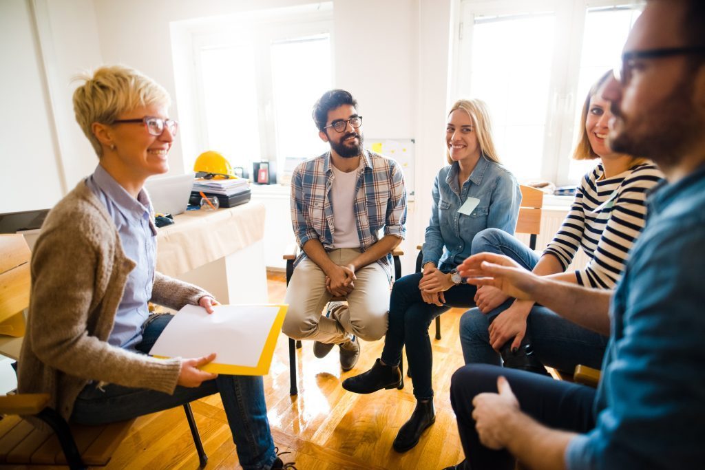 Diverse group in therapy session discussing alcohol recovery