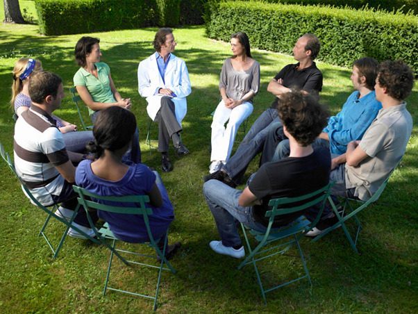 People sitting in a circle outdoors for group therapy session