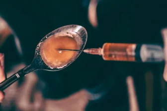 Close-up of spoon and syringe highlighting heroin addiction issues