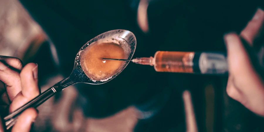 Close-up of spoon and syringe highlighting heroin addiction issues