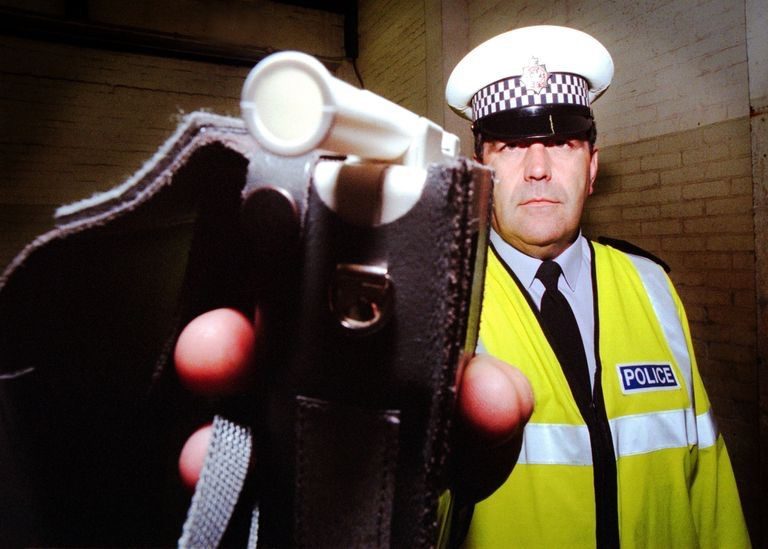 Police officer holding a breathalyzer, related to how long alcohol stays in your system.