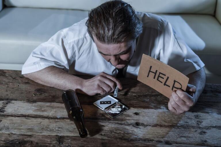 Man struggling with alcohol, holding help sign, feeling trapped; how to beat addiction