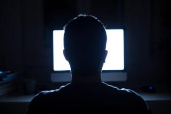 Silhouette of a person facing a computer screen, highlighting internet addiction.