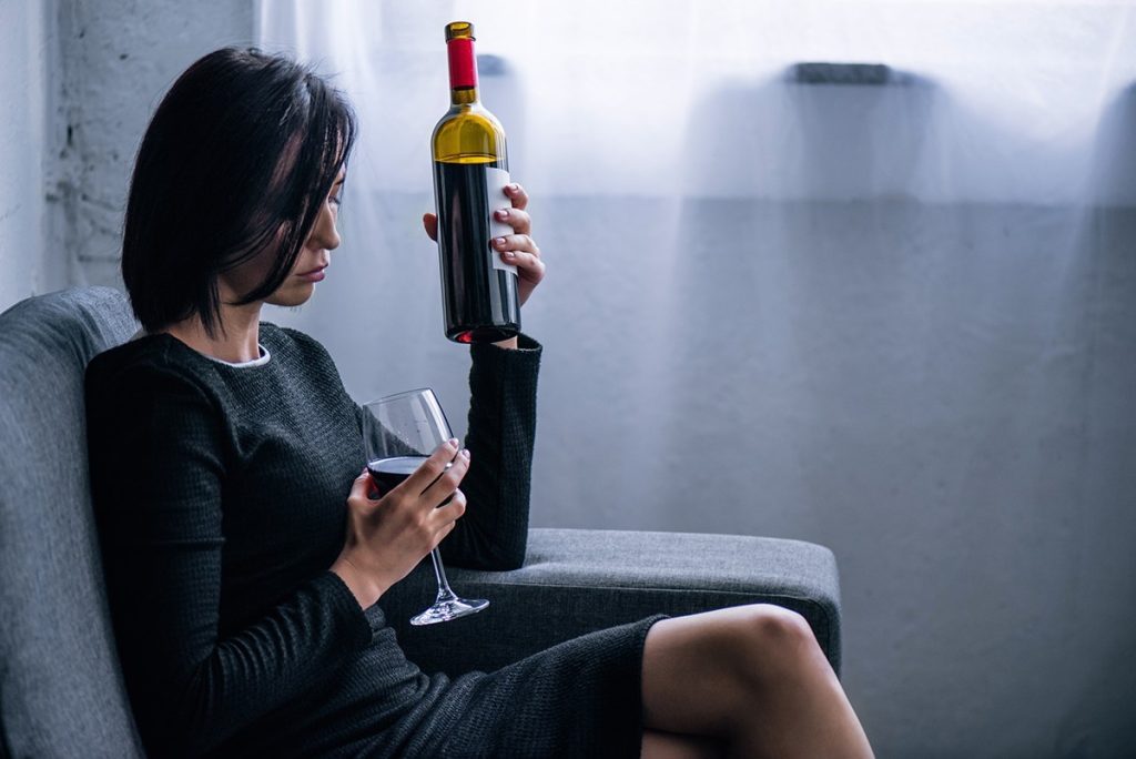 Woman contemplating wine glass, exploring is alcohol a depressant