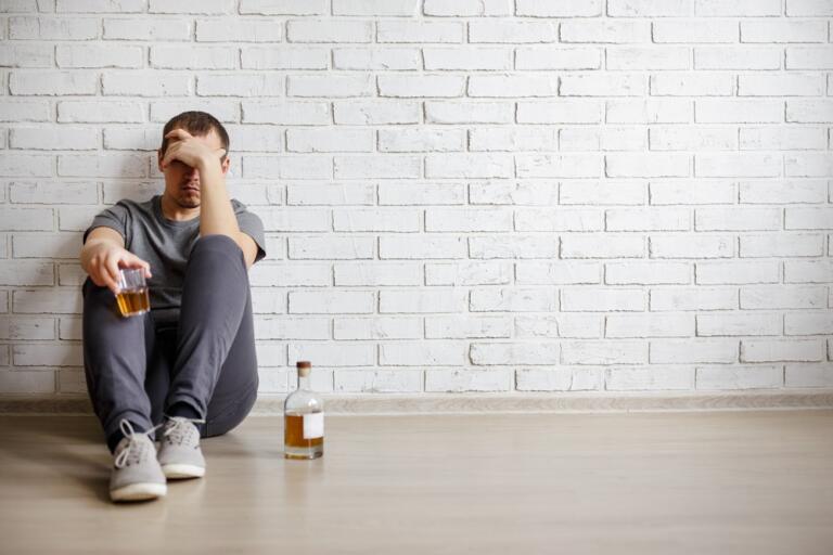 Man sitting with drink, contemplating: Is Alcoholism a Disease?