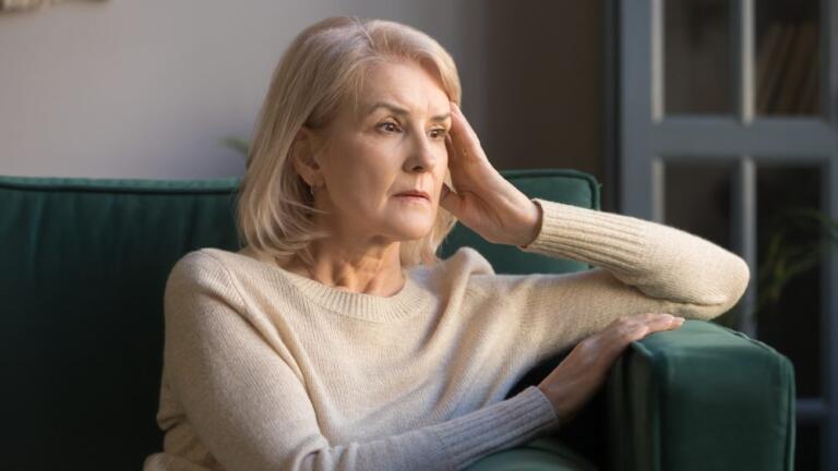 Elderly woman reflecting on losing a loved one to addiction, feeling sad