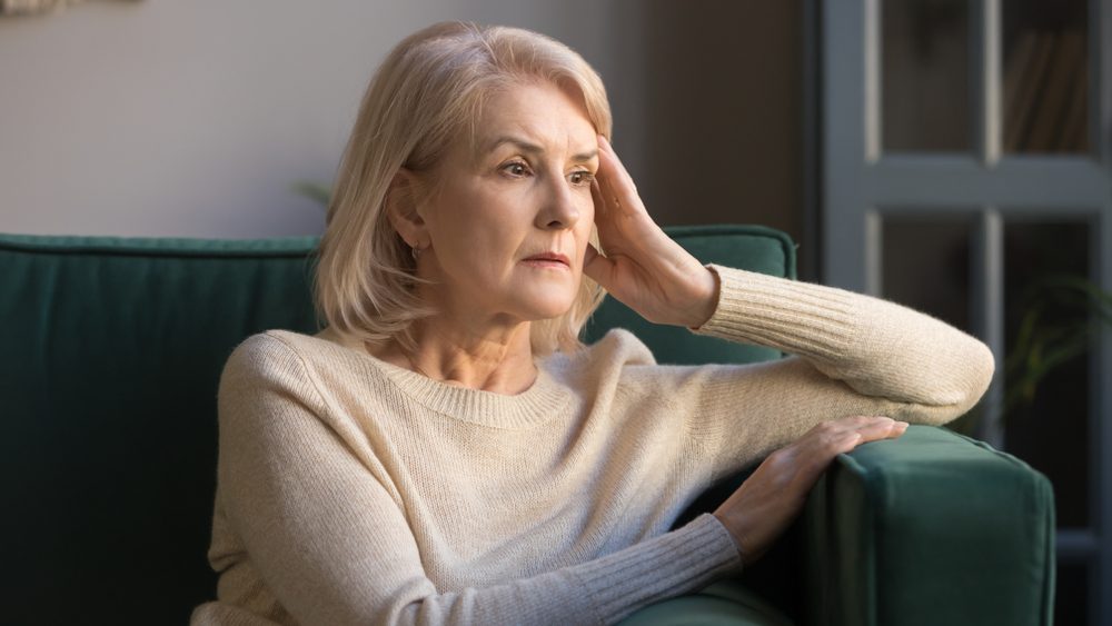 Elderly woman reflecting on losing a loved one to addiction, feeling sad