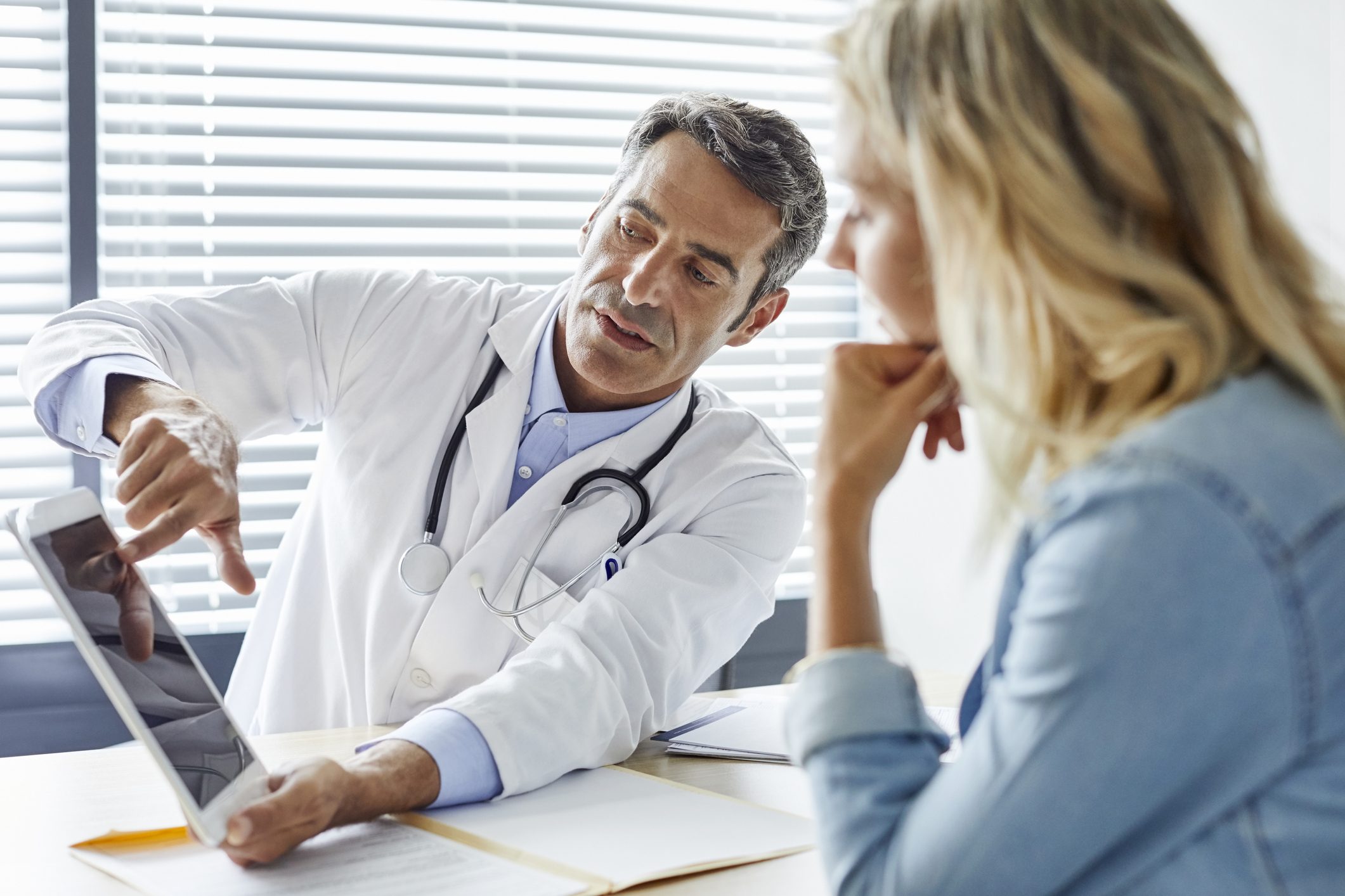 Doctor consulting patient about luxury rehab program on tablet