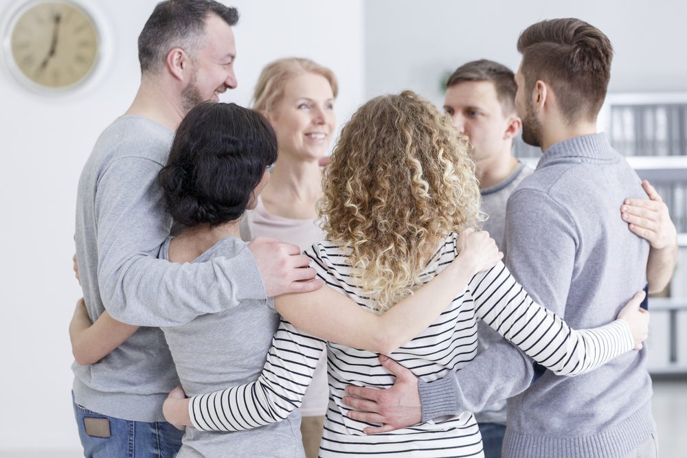 Support group embracing to overcome addicts excuses in rehab