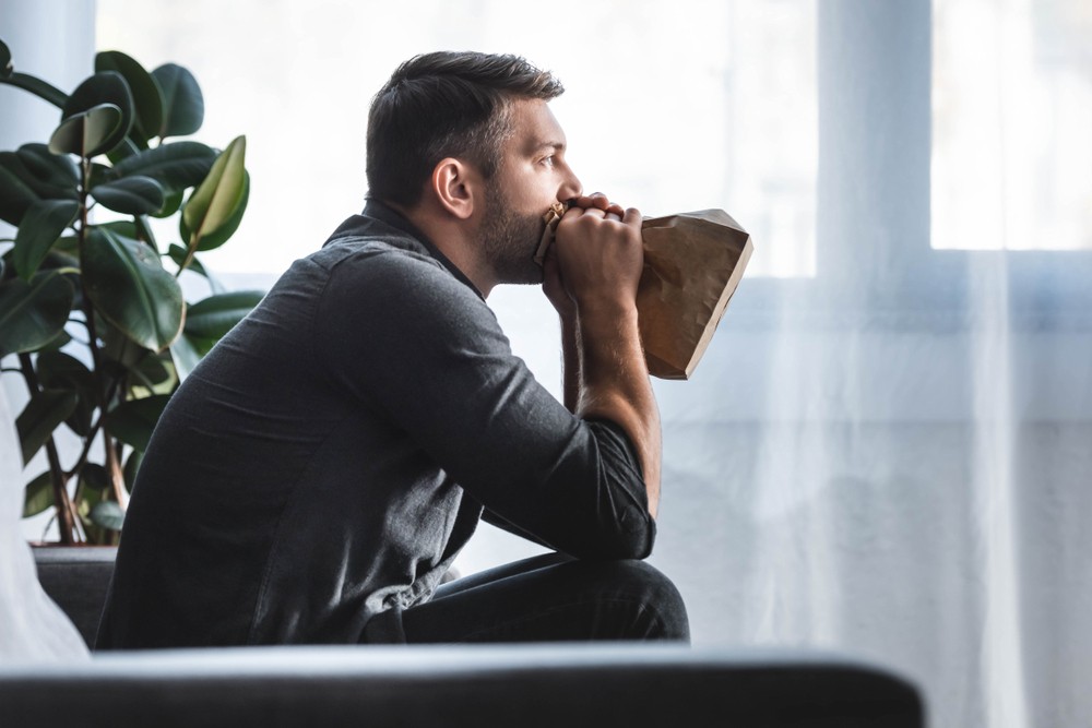 Man experiencing panic attacks after drinking, using breathing techniques in rehab.