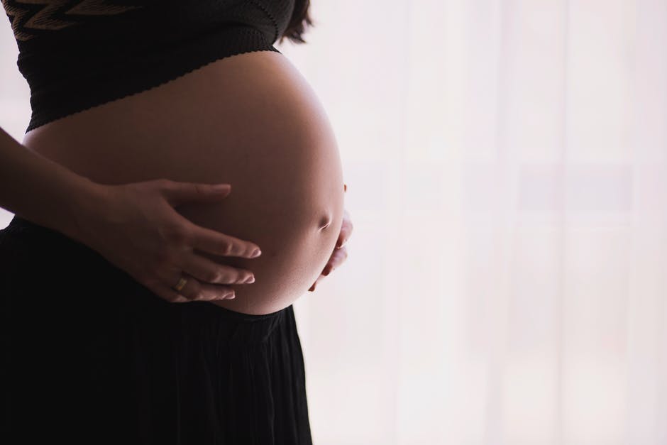 Pregnant person holding belly, focusing on alcohol-free recovery journey