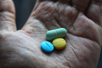 Hand holding various prescription drugs for addiction recovery