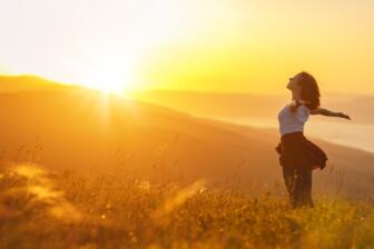 Woman embracing sunset in nature, symbolizing recovery quotes